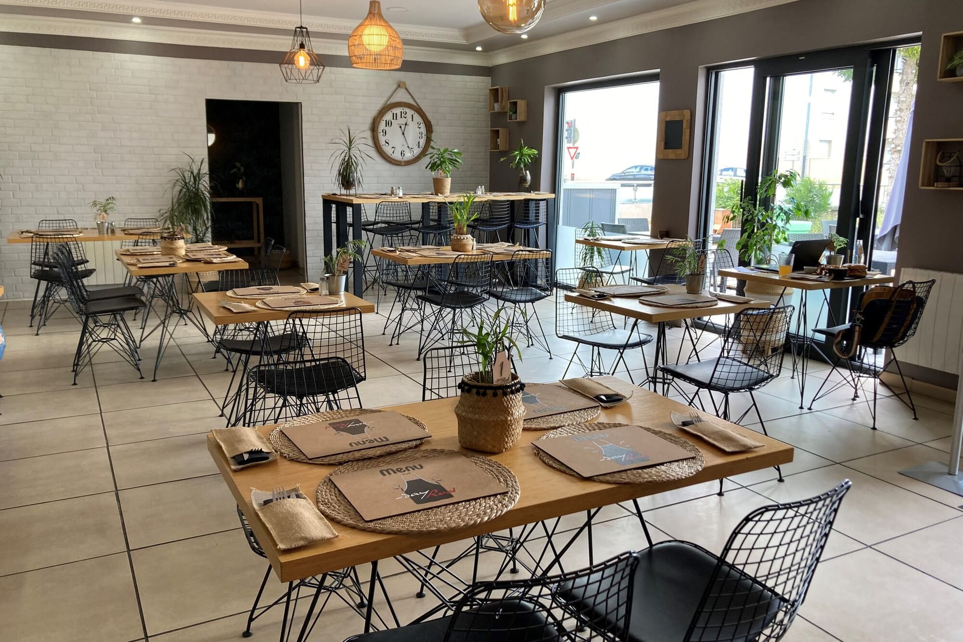 Salle du restaurant Sayred avec tables bois, chaises métal noir et vue sur la baie vitrée